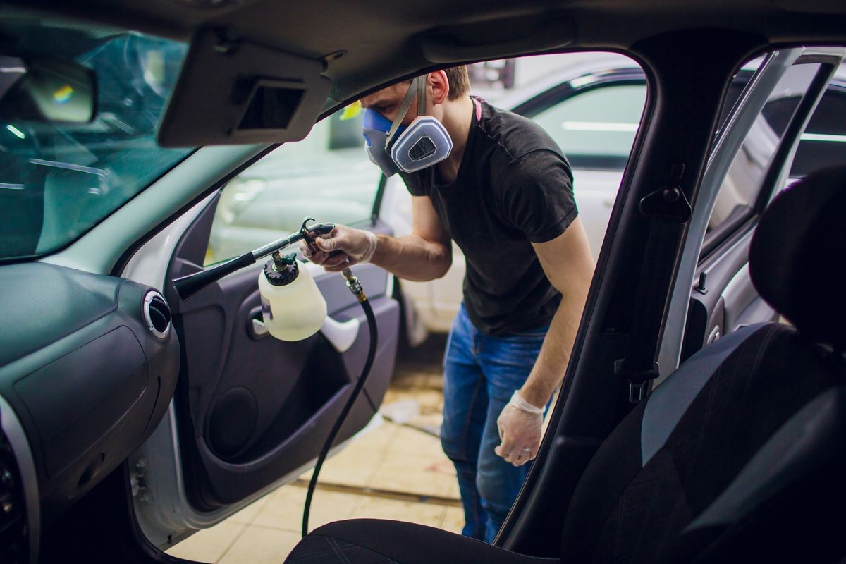 Car detailing Handsome man cleaning car with hot steam