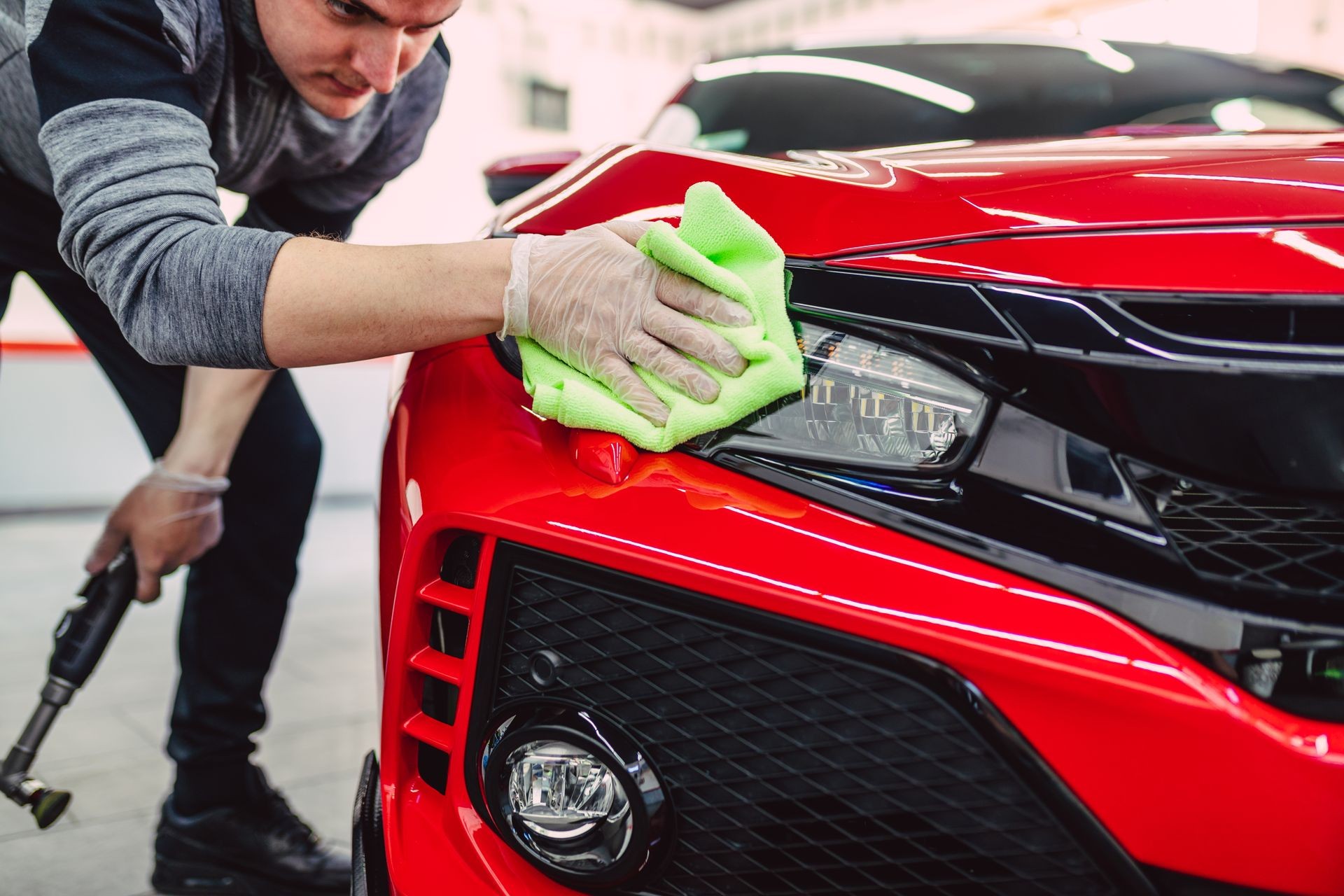 A man cleaning car with cloth, car detailing (or valeting) concept. Selective focus. 